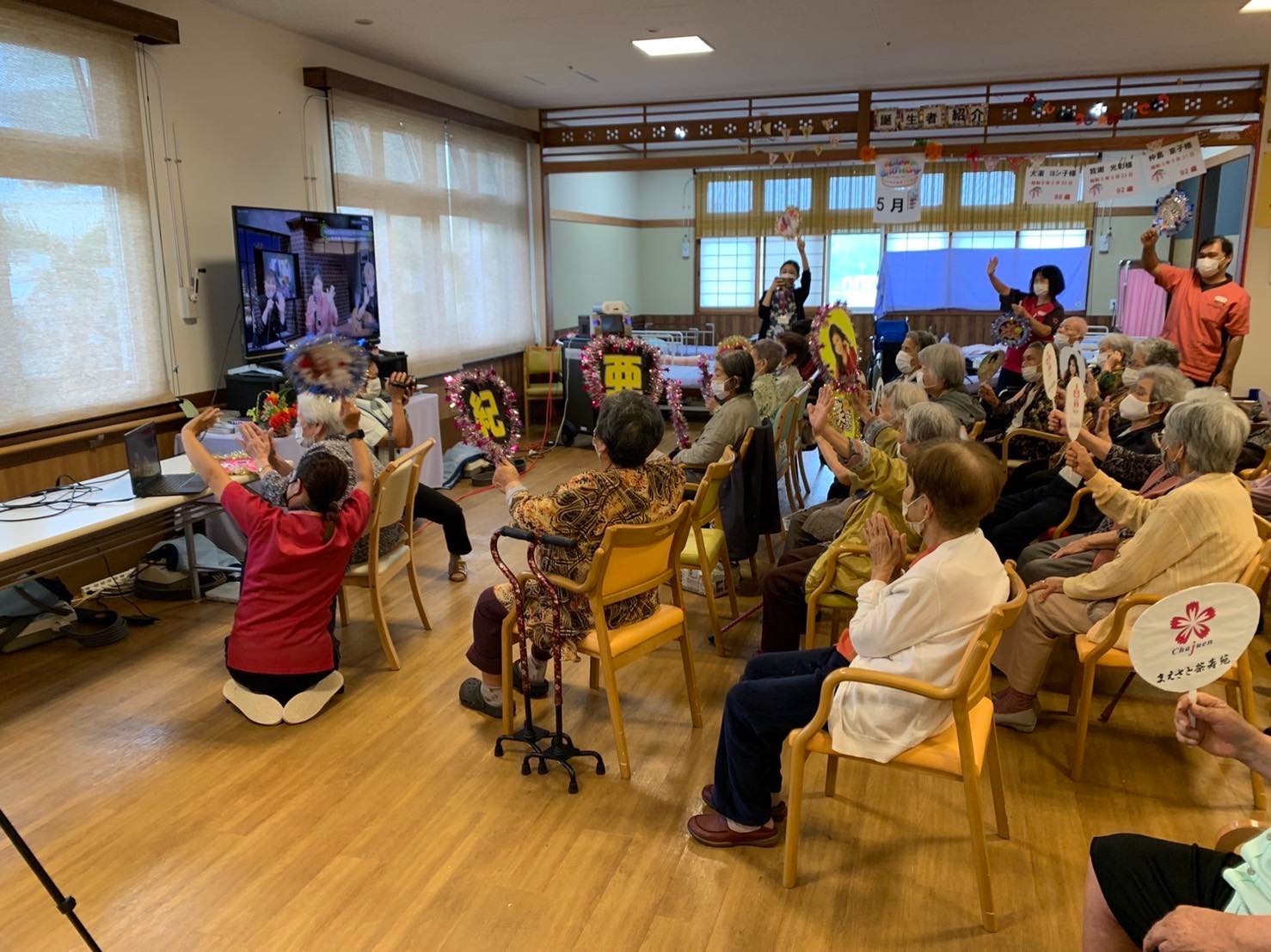 介護施設のフロアでオンラインコンサートを視聴する様子