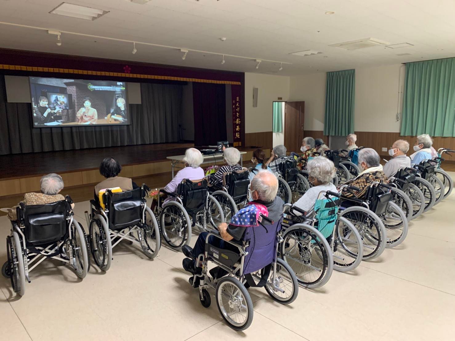 介護施設ホールでオンライン対話型コンサートを視聴している様子